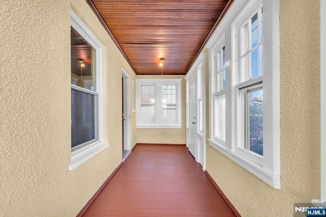 unfurnished sunroom featuring wooden ceiling and plenty of natural light