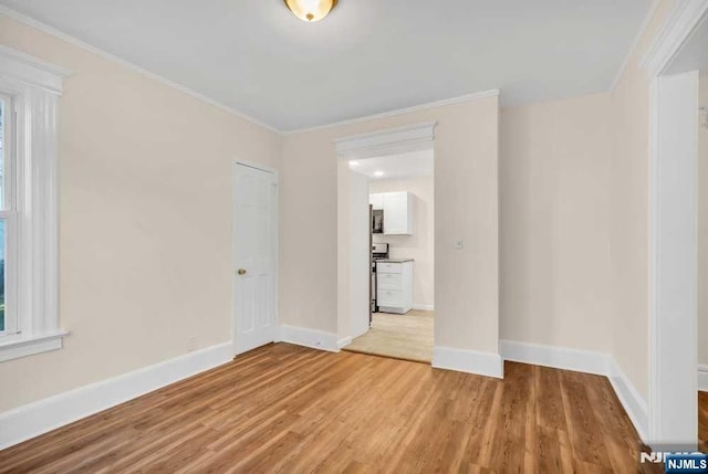 unfurnished room featuring crown molding, light wood-style flooring, and baseboards