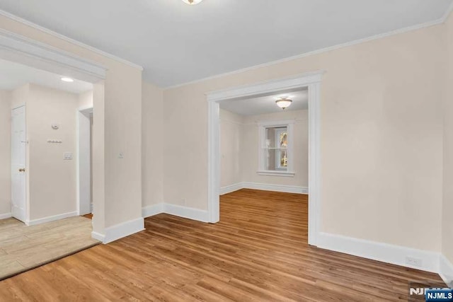 empty room featuring crown molding, baseboards, and wood finished floors