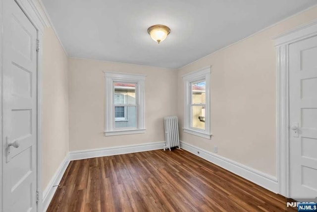 empty room with radiator heating unit, baseboards, and dark wood finished floors