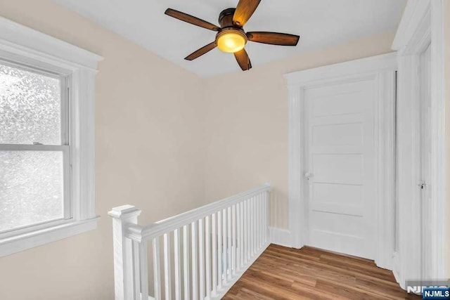 hall with wood finished floors and an upstairs landing