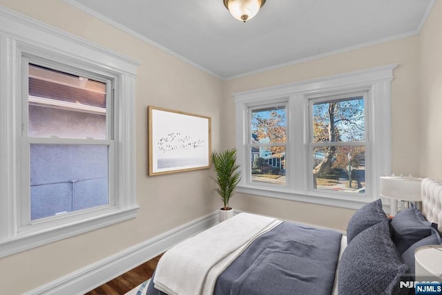 bedroom with ornamental molding, wood finished floors, and baseboards