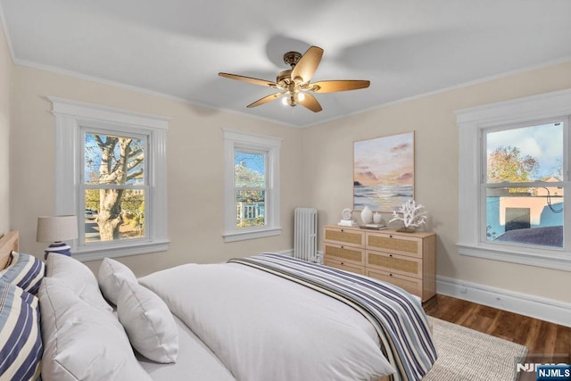 bedroom with baseboards, dark wood finished floors, a ceiling fan, radiator, and ornamental molding