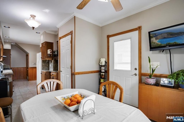 dining space featuring a ceiling fan, wainscoting, crown molding, and light tile patterned floors