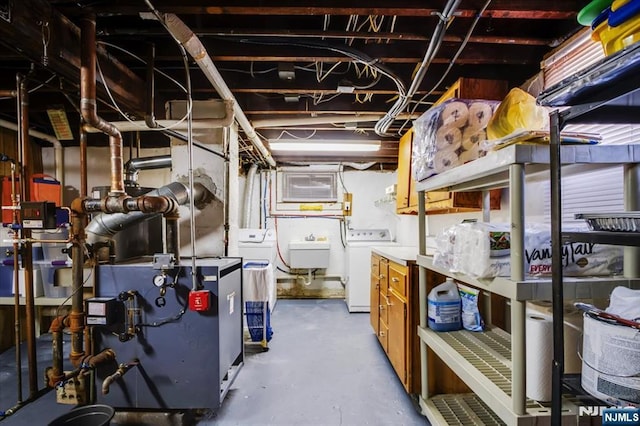 utility room with washing machine and dryer, a heating unit, and a sink