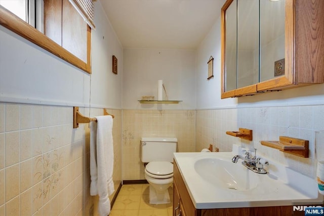 bathroom with tile patterned flooring, wainscoting, vanity, and toilet