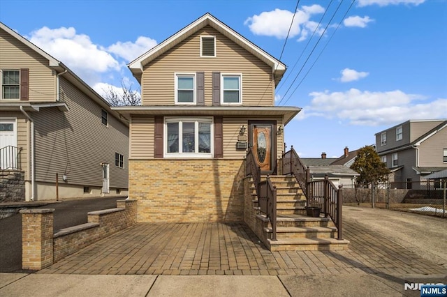 traditional-style home with a patio area, fence, and brick siding