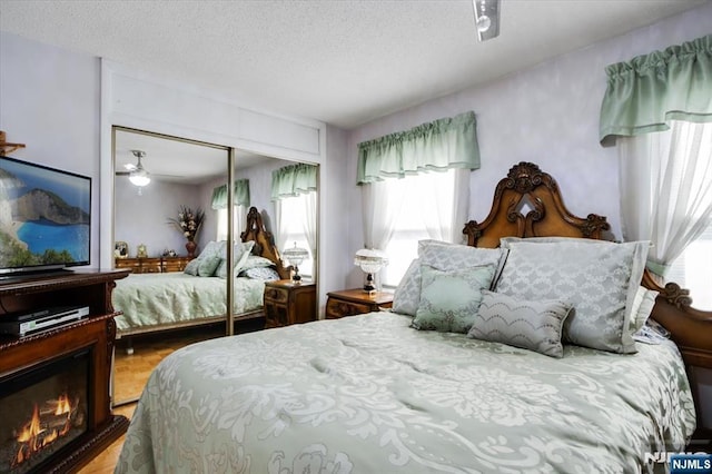 bedroom featuring a glass covered fireplace, a closet, and a textured ceiling