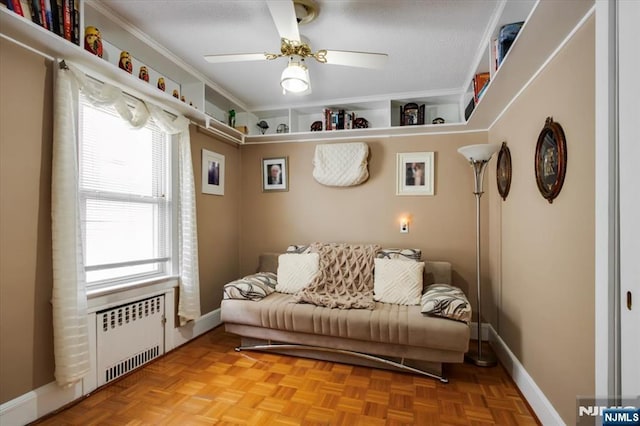 sitting room with baseboards, crown molding, a ceiling fan, and radiator