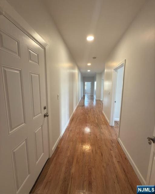 corridor with recessed lighting, wood finished floors, and baseboards