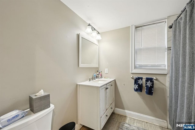 bathroom featuring toilet, wood tiled floor, baseboards, and vanity