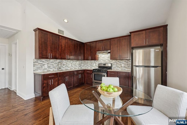 kitchen with tasteful backsplash, lofted ceiling, visible vents, appliances with stainless steel finishes, and under cabinet range hood