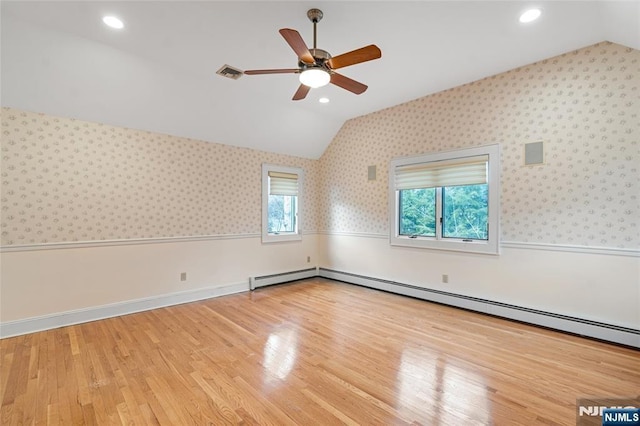 unfurnished room with lofted ceiling, wainscoting, visible vents, and wallpapered walls