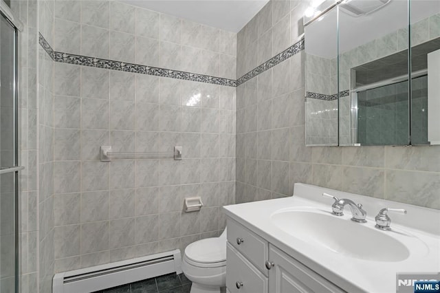 bathroom with toilet, tile patterned flooring, baseboard heating, vanity, and tile walls