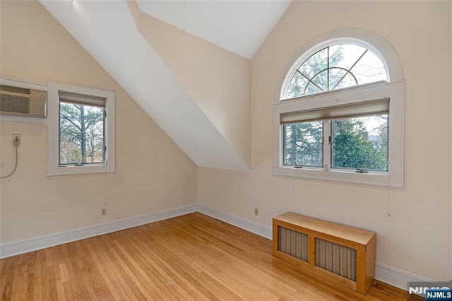 bonus room featuring a wall unit AC, plenty of natural light, wood-type flooring, and baseboards