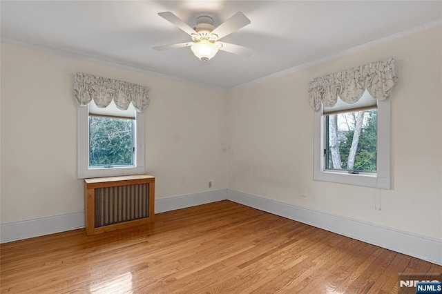 unfurnished room featuring baseboards, a ceiling fan, radiator, ornamental molding, and light wood-style floors