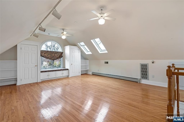 additional living space with a baseboard heating unit, ceiling fan, lofted ceiling with skylight, and light wood finished floors