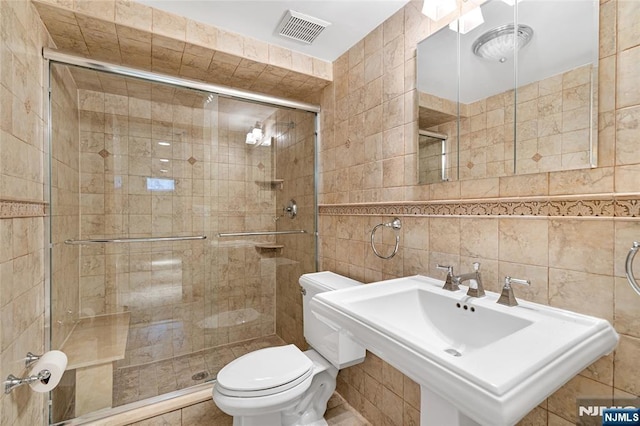 full bathroom with toilet, a stall shower, visible vents, and tile walls