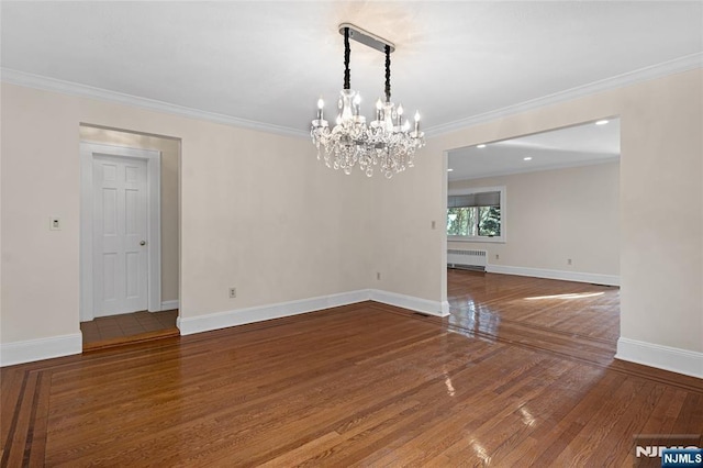 empty room featuring crown molding, wood-type flooring, baseboards, and radiator