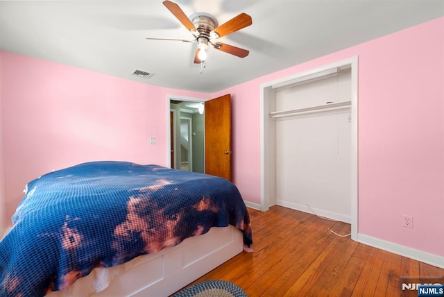 bedroom with hardwood / wood-style floors, baseboards, visible vents, and a ceiling fan