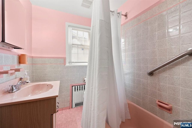 full bathroom featuring shower / tub combo with curtain, radiator, tile walls, wainscoting, and vanity