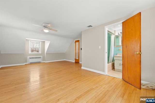 bonus room featuring radiator, baseboards, vaulted ceiling, light wood-style floors, and a ceiling fan