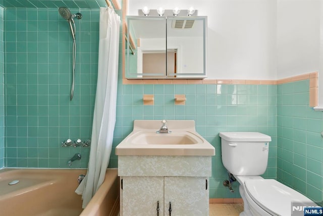 full bathroom with tile walls, vanity, toilet, and shower / tub combo