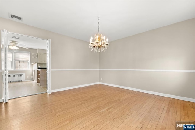 empty room featuring hardwood / wood-style floors, radiator, baseboards, and a chandelier