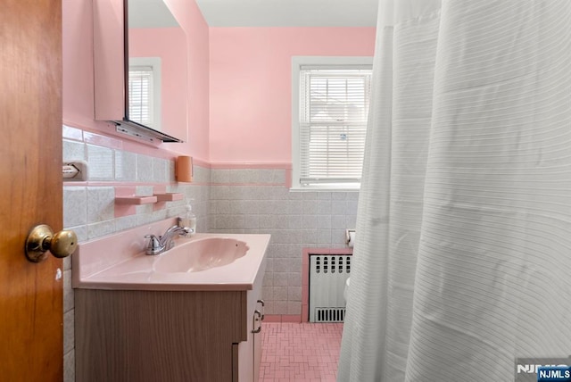 bathroom featuring curtained shower, a wainscoted wall, vanity, radiator heating unit, and tile walls