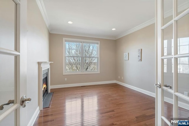 unfurnished living room featuring a fireplace with flush hearth, baseboards, crown molding, and wood finished floors