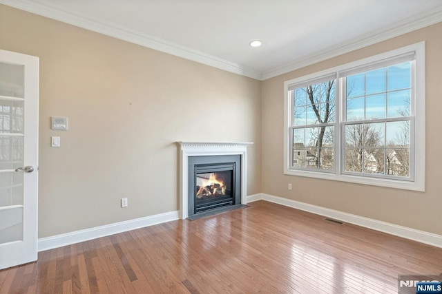 unfurnished living room featuring ornamental molding, visible vents, hardwood / wood-style floors, and baseboards