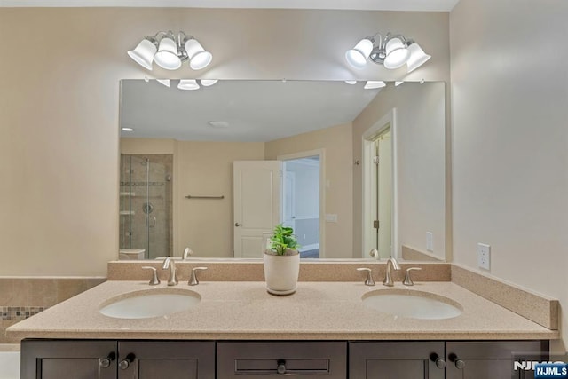 bathroom with double vanity, a stall shower, and a sink