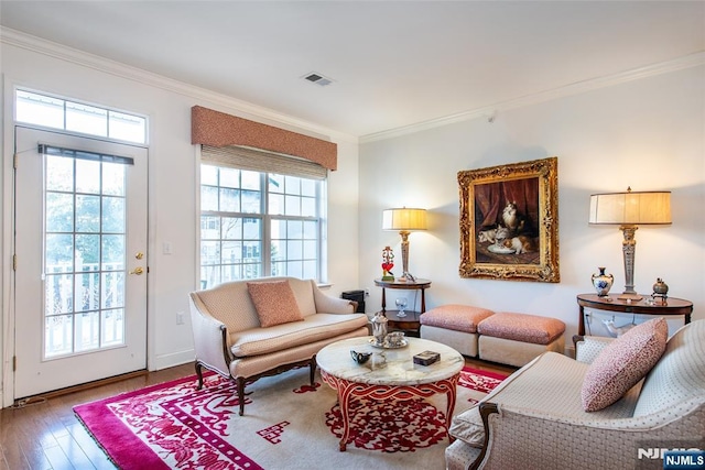 living room with ornamental molding, visible vents, and plenty of natural light