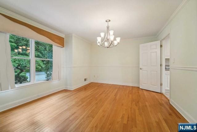 empty room with crown molding, light wood-style flooring, baseboards, and an inviting chandelier