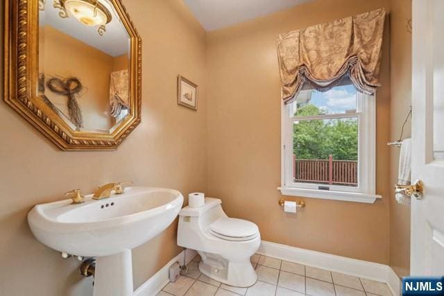 half bath with tile patterned flooring, baseboards, and toilet