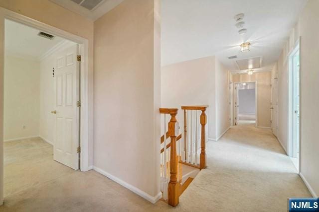 hall featuring baseboards, visible vents, light colored carpet, and an upstairs landing