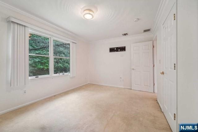 empty room featuring baseboards, visible vents, ornamental molding, and light colored carpet