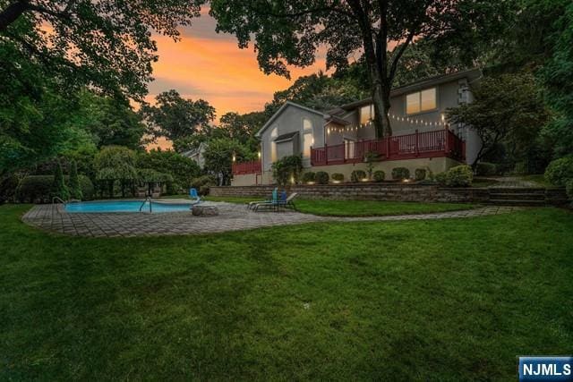 yard at dusk with an outdoor pool and a patio