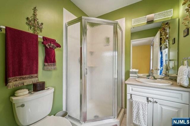 bathroom with toilet, a stall shower, and vanity