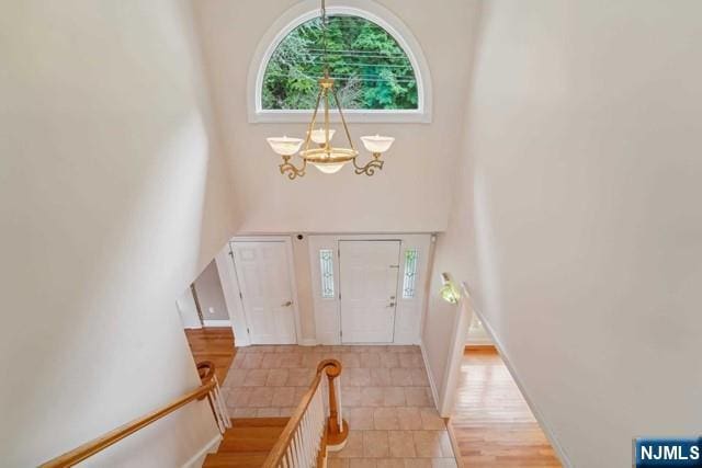 entryway with a chandelier, a towering ceiling, and baseboards