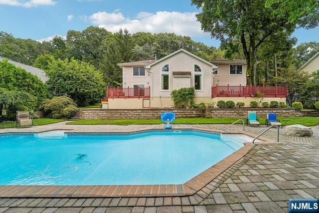 outdoor pool with a patio area and a deck