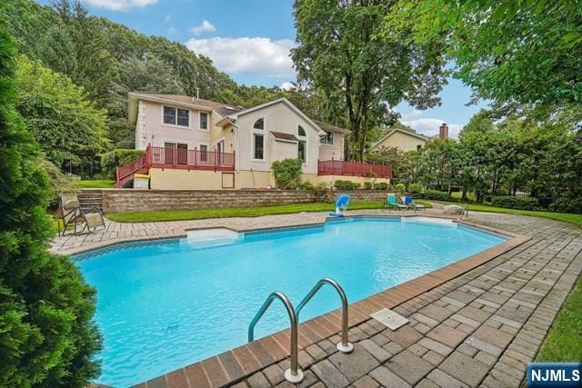 outdoor pool featuring a patio area and a wooden deck