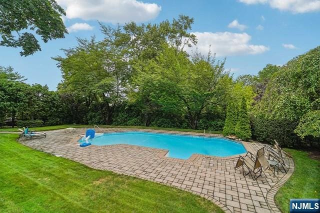 outdoor pool with a lawn and a patio area