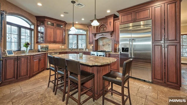 kitchen with a breakfast bar, stone tile flooring, visible vents, appliances with stainless steel finishes, and a sink