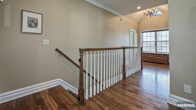 corridor featuring baseboards, hardwood / wood-style flooring, an inviting chandelier, vaulted ceiling, and an upstairs landing