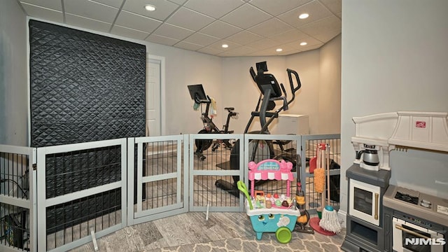 exercise area featuring recessed lighting, a drop ceiling, and wood finished floors