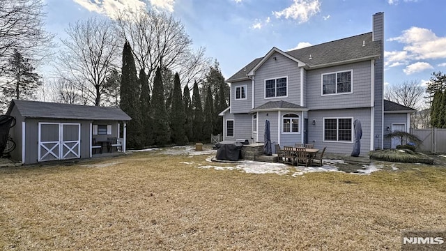 back of property with an outbuilding, a lawn, a chimney, and a storage shed