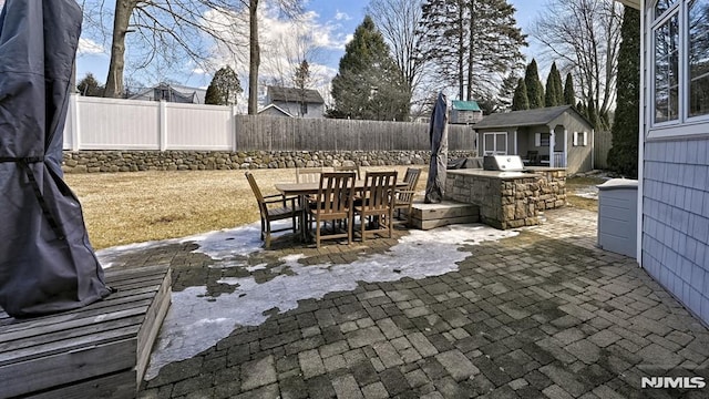 view of patio with a fenced backyard, outdoor dining area, area for grilling, and an outbuilding