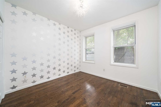 spare room with dark wood-style floors, baseboards, visible vents, and wallpapered walls