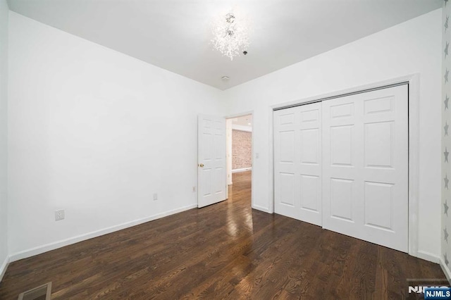 unfurnished bedroom featuring dark wood-style floors, a closet, visible vents, and baseboards